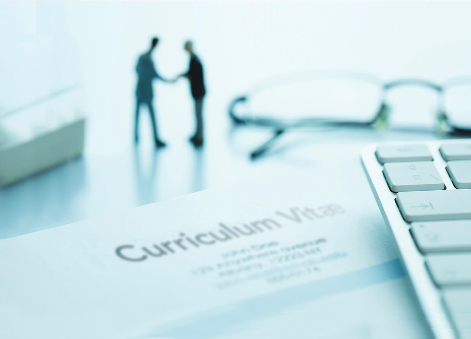 Silhouettes de deux personnes se serrant la main, clavier d'ordinateur, curriculum vitae.