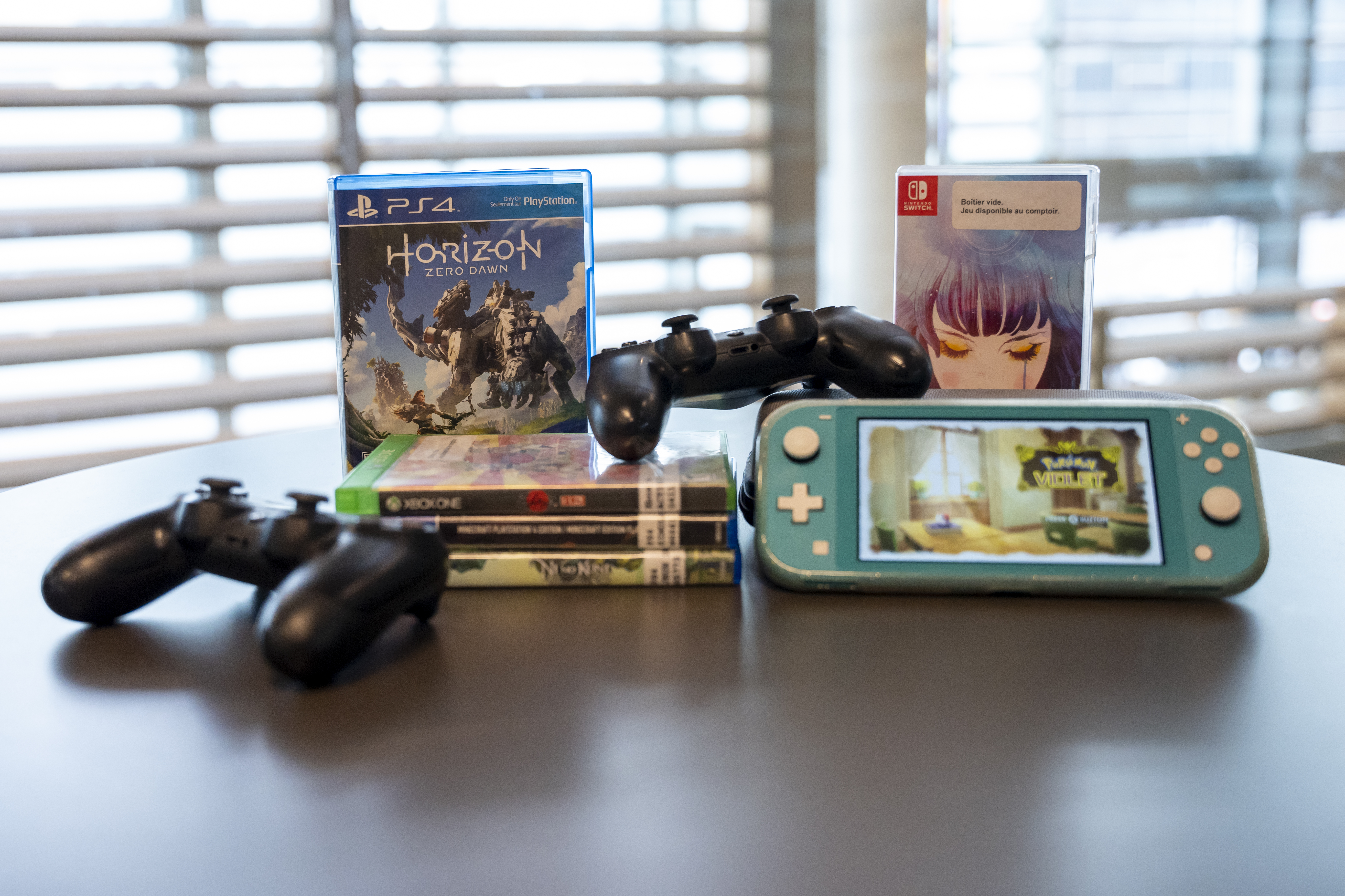 Deux manettes de jeu vidéo, Nintendo Switch et 5 boîtiers de jeux dont Horizon Zero Dawn.