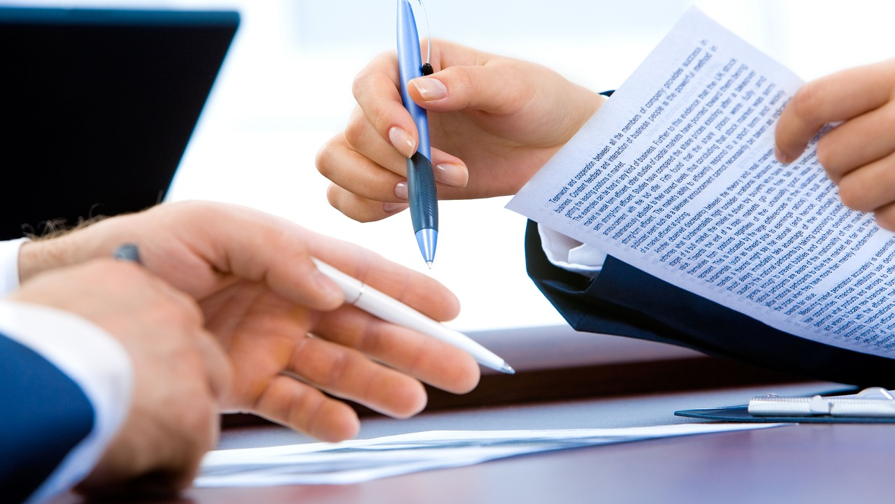 Mains de deux personnes qui semblent signer un contrat.