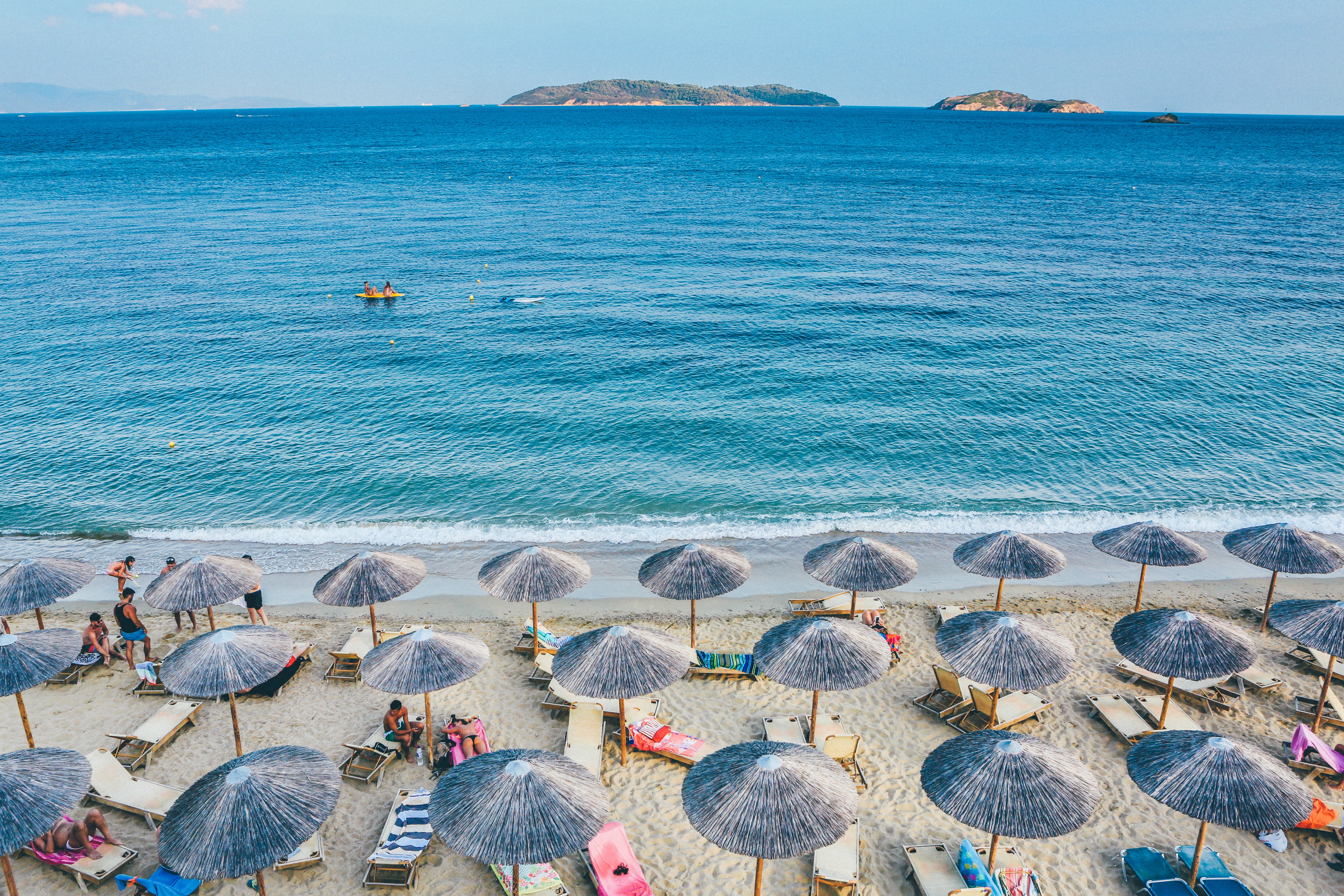 Nombreux parasols et chaises longues sur la plage, devant la mer.