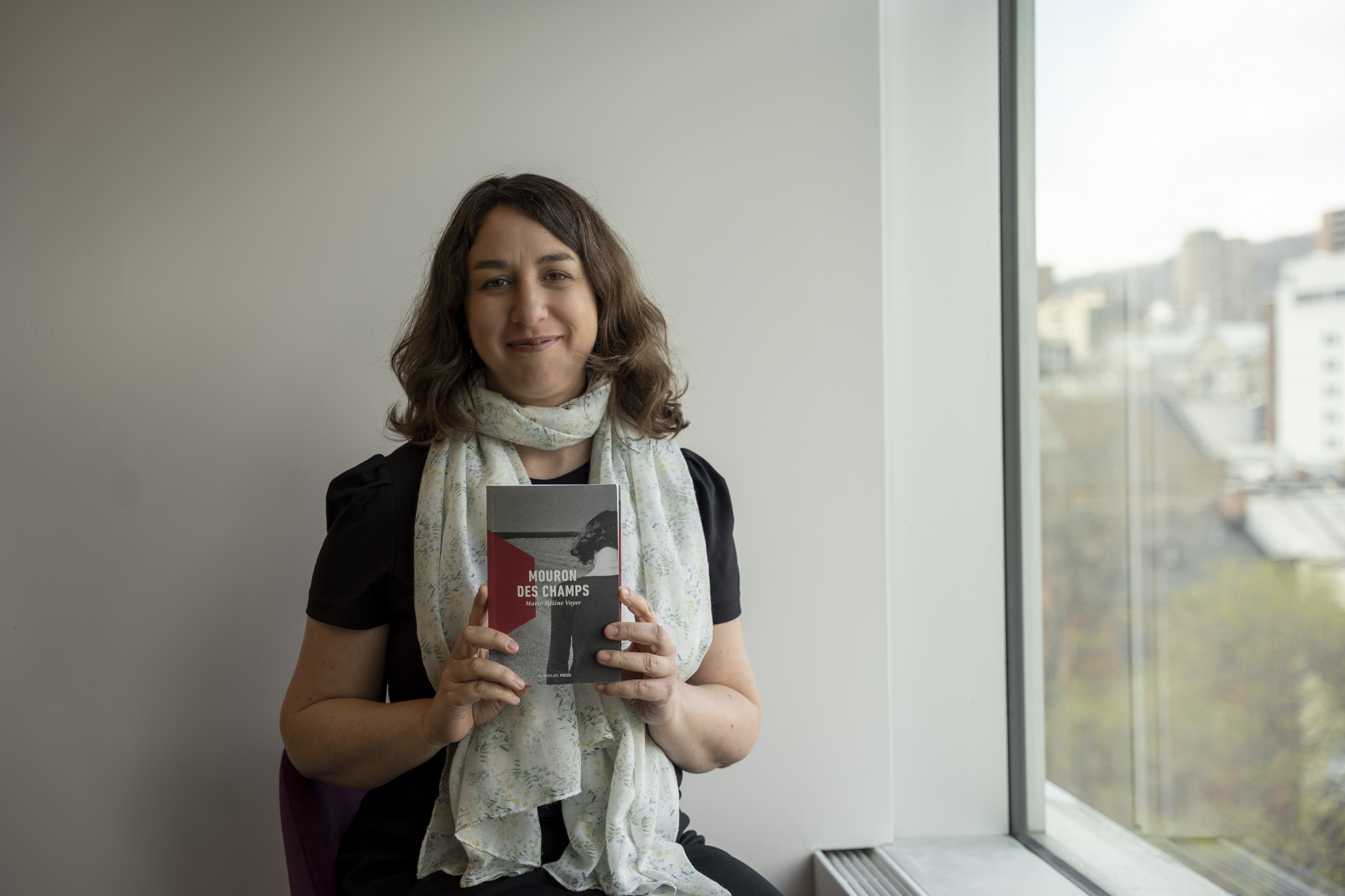 Esther Laforce, bibliothécaire de la Grande Bibliothèque et membre du balado « Signets au féminin », tenant le recueil « Mouron des champs » de Marie-Hélène Voyer
