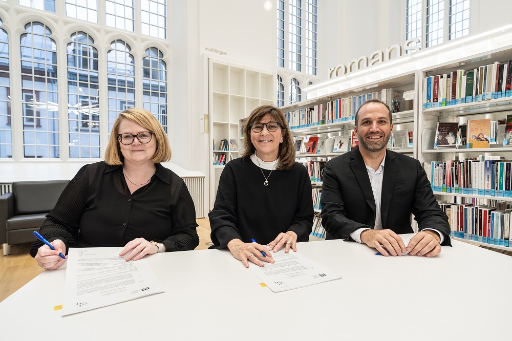 Deux femmes et un homme tout sourire assis à une table.