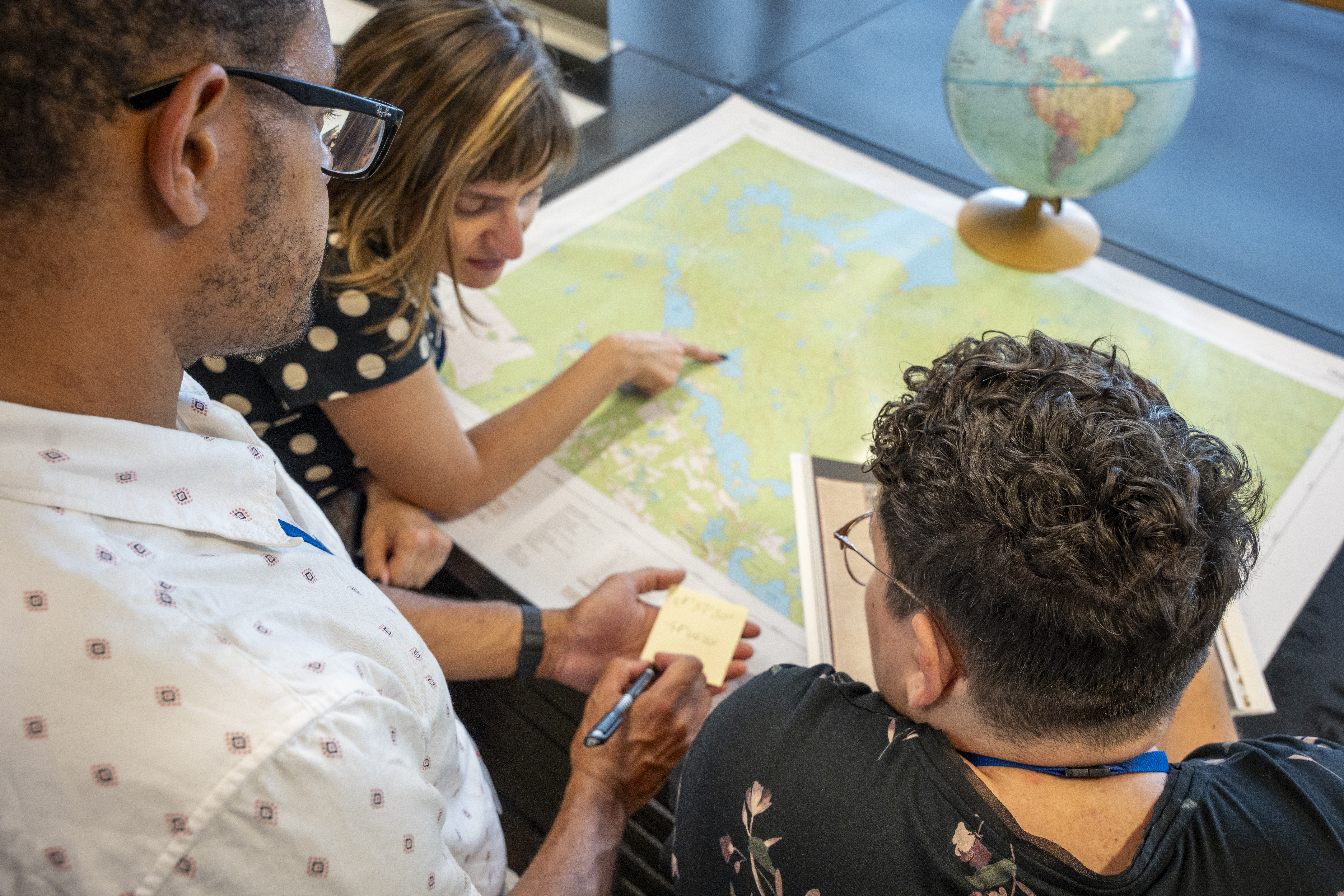 Trois personnes observent une carte géographique.