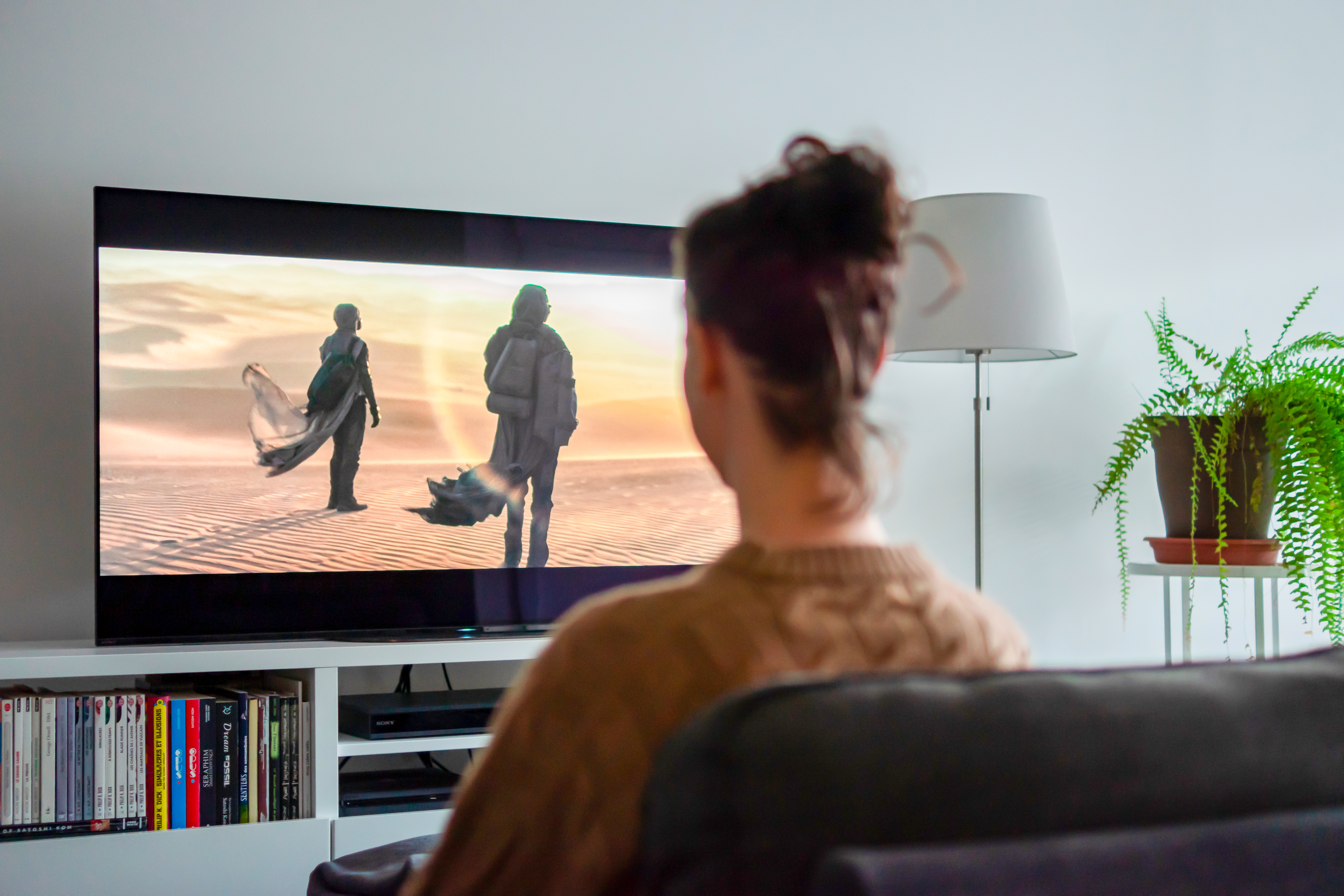 Une jeune femme regarde un film sur un écran de télévision.