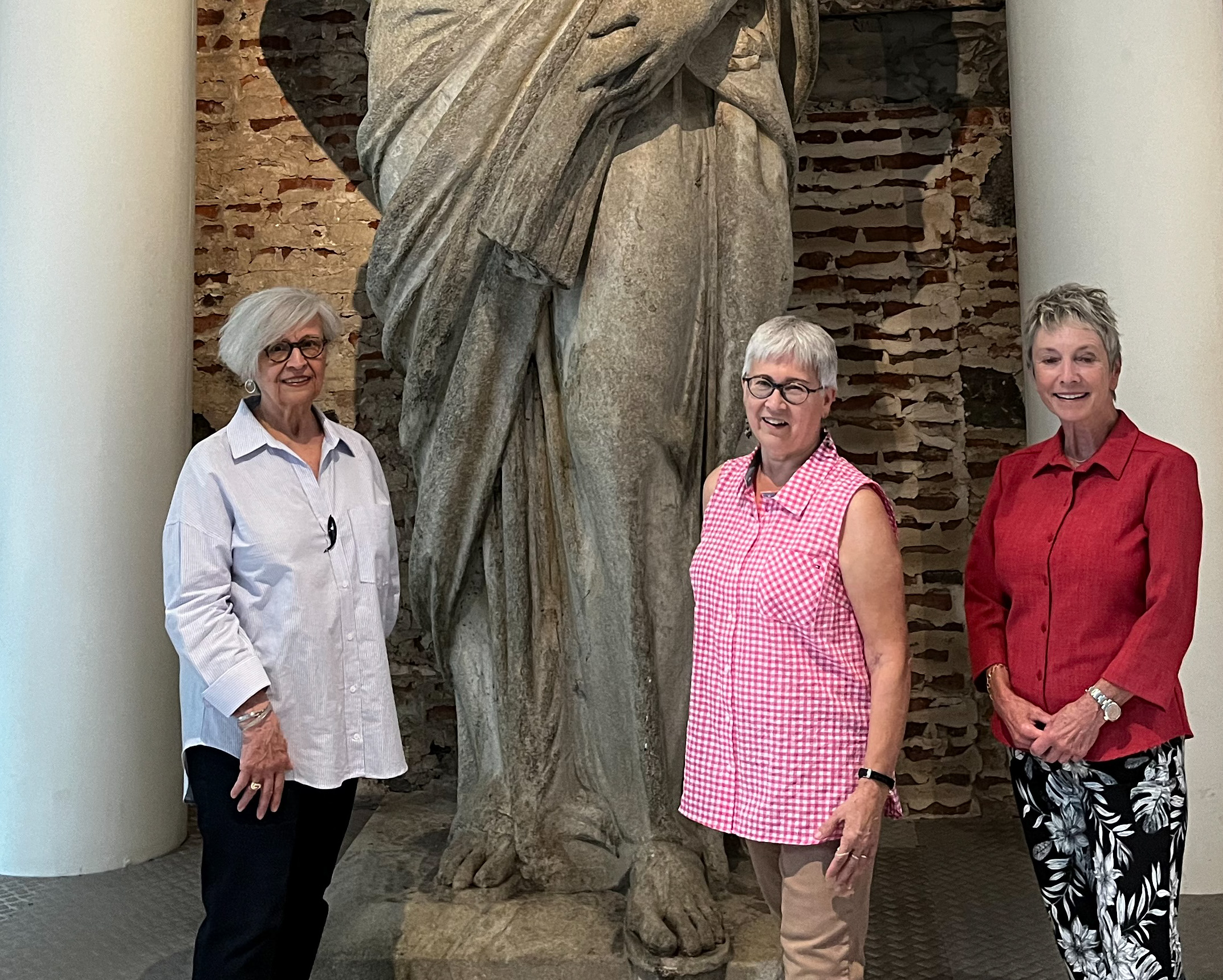 Trois personnes devant des colonnes et une statue géante.