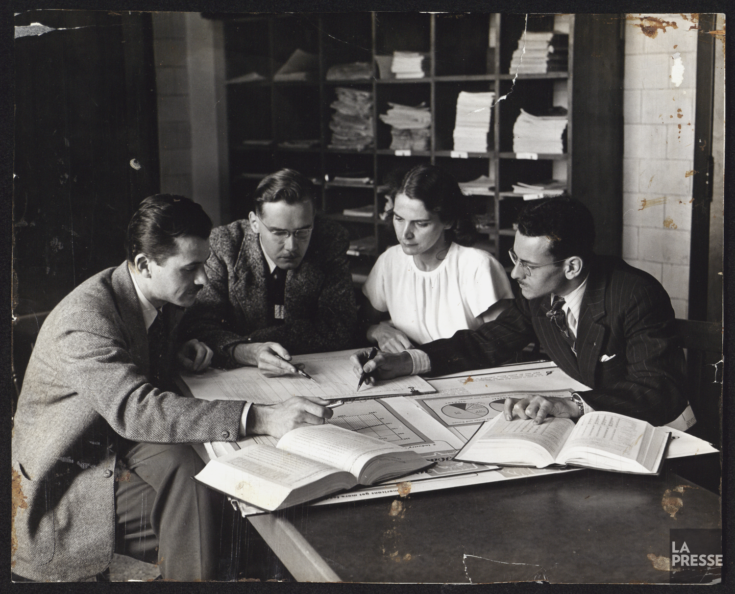 Quatre personnes regardent des plans et des livres d'étude.