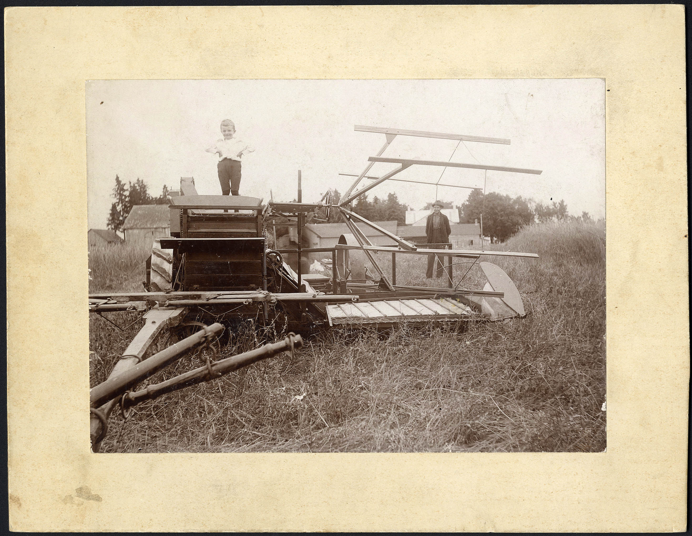 Photo noir et blanc d'un enfant et d'un homme posant près d'une machine agricole.