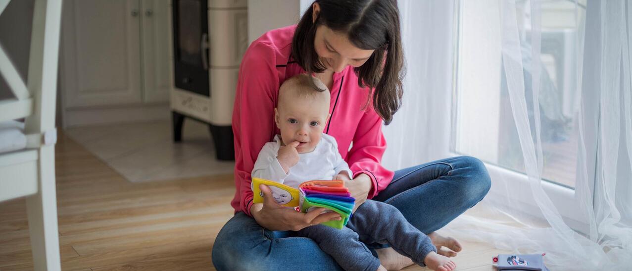 Une femme montre un livre à un bébé.