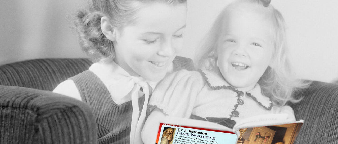 Une enfant fait la lecture à sa petite soeur.