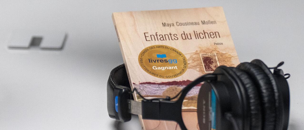 Micro pointé vers le recueil "Enfants du lichen" près d'un casque