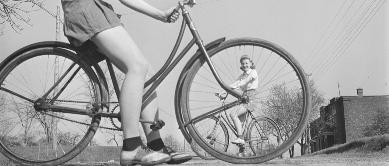 Photo ancienne présentant deux jeunes femmes à vélo.
