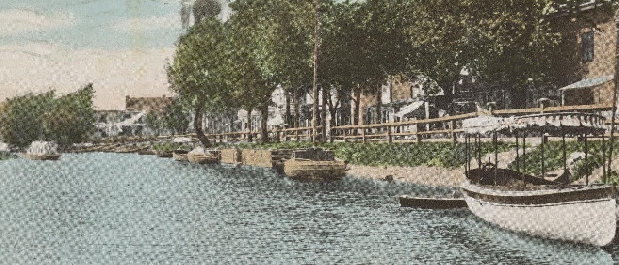 Vue du canal de Lachine, sur laquelle on aperçoit des canots accostés le long de quais. 