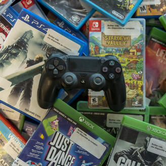 Manette de PS4 sur une pile de boitiers de jeux vidéo