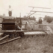 Photo noir et blanc d'un enfant et d'un homme posant près d'une machine agricole.